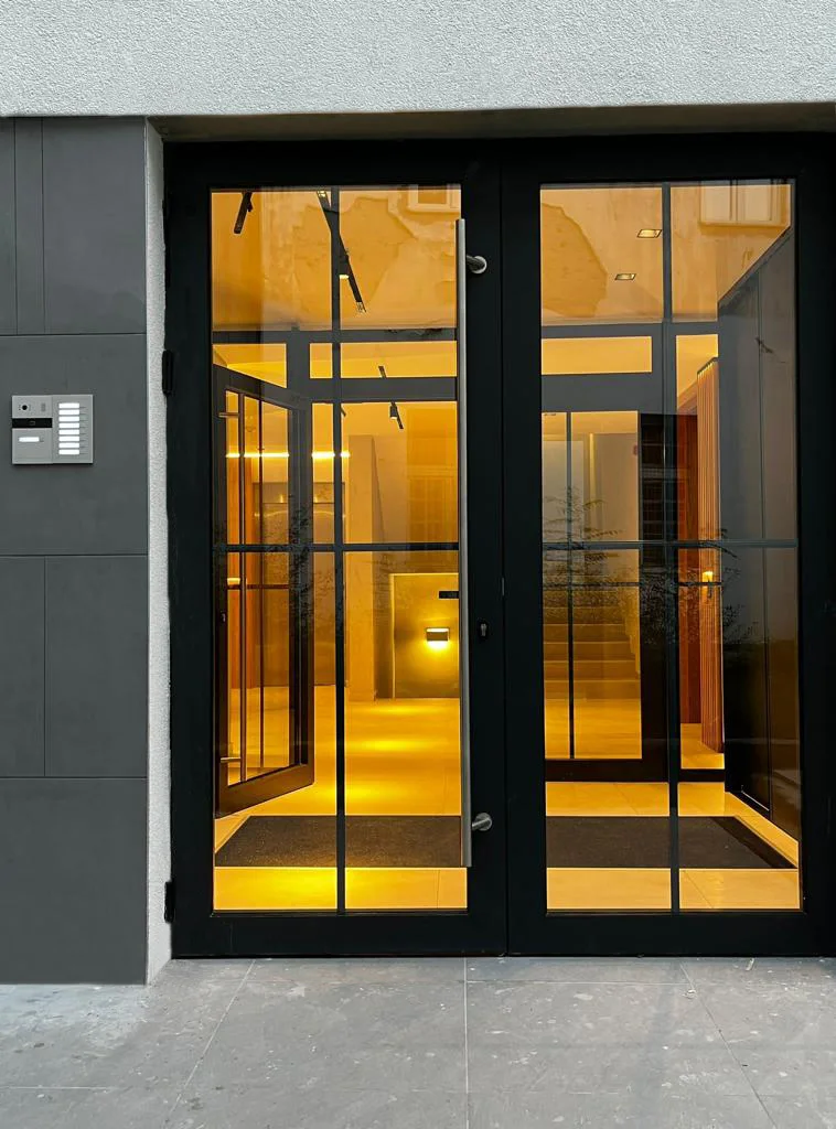 Residential building on Ložnička, Belgrade: glazed entrance doors with the lit hall behind