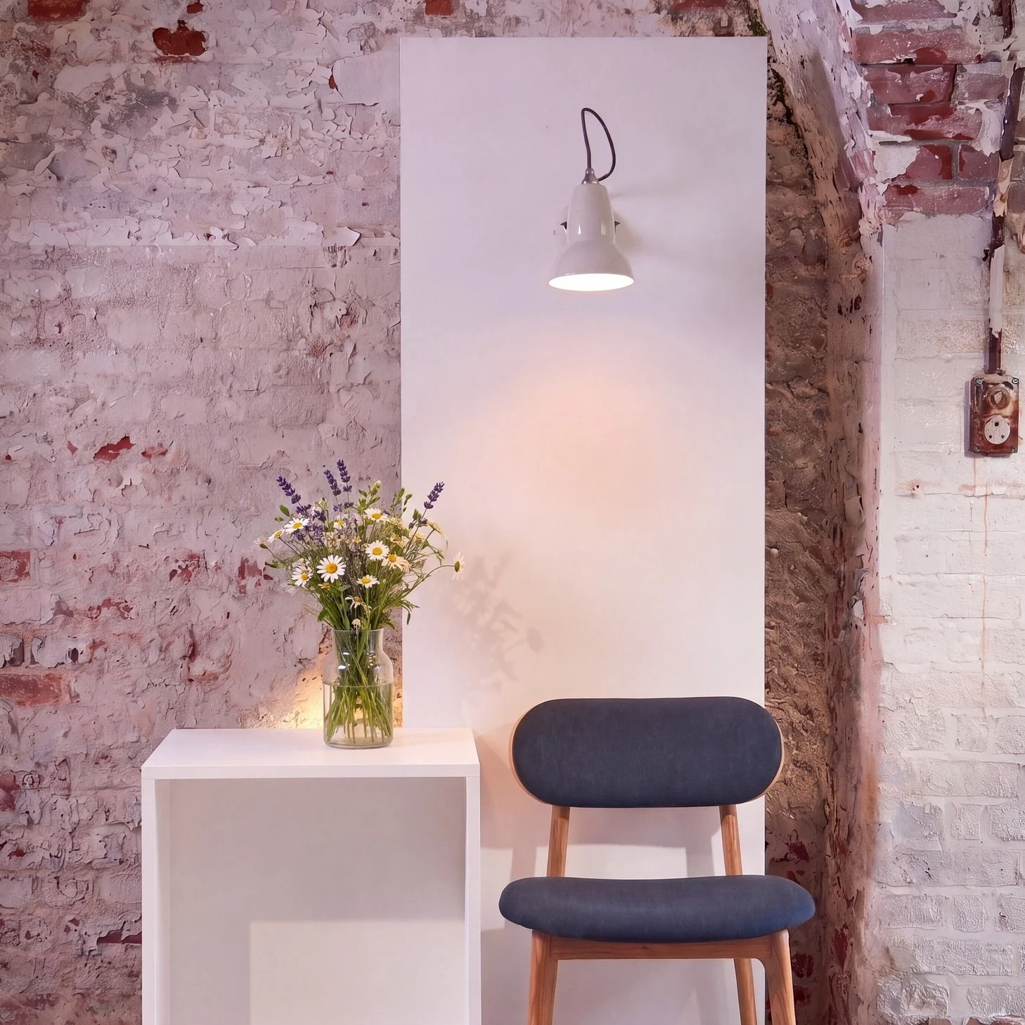 Anglepoise Original 1227 Mini wall light in white above a chair, against a painted brick wall