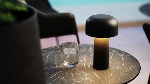 Flos Bellhop portable lamp in matt black on a marble side table by a pool