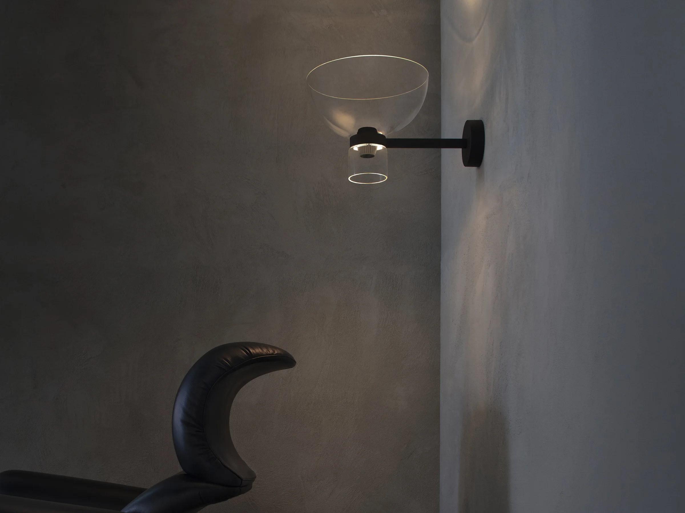 Flos Nocturne Wall Bowl on a grey wall above a black armchair